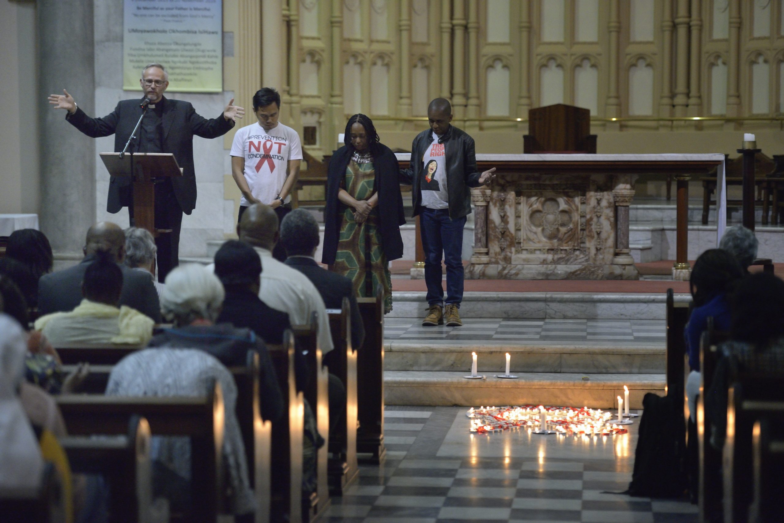 JP preaching from a cathedral pulpit with his arms open; candles burn on the chancel floor