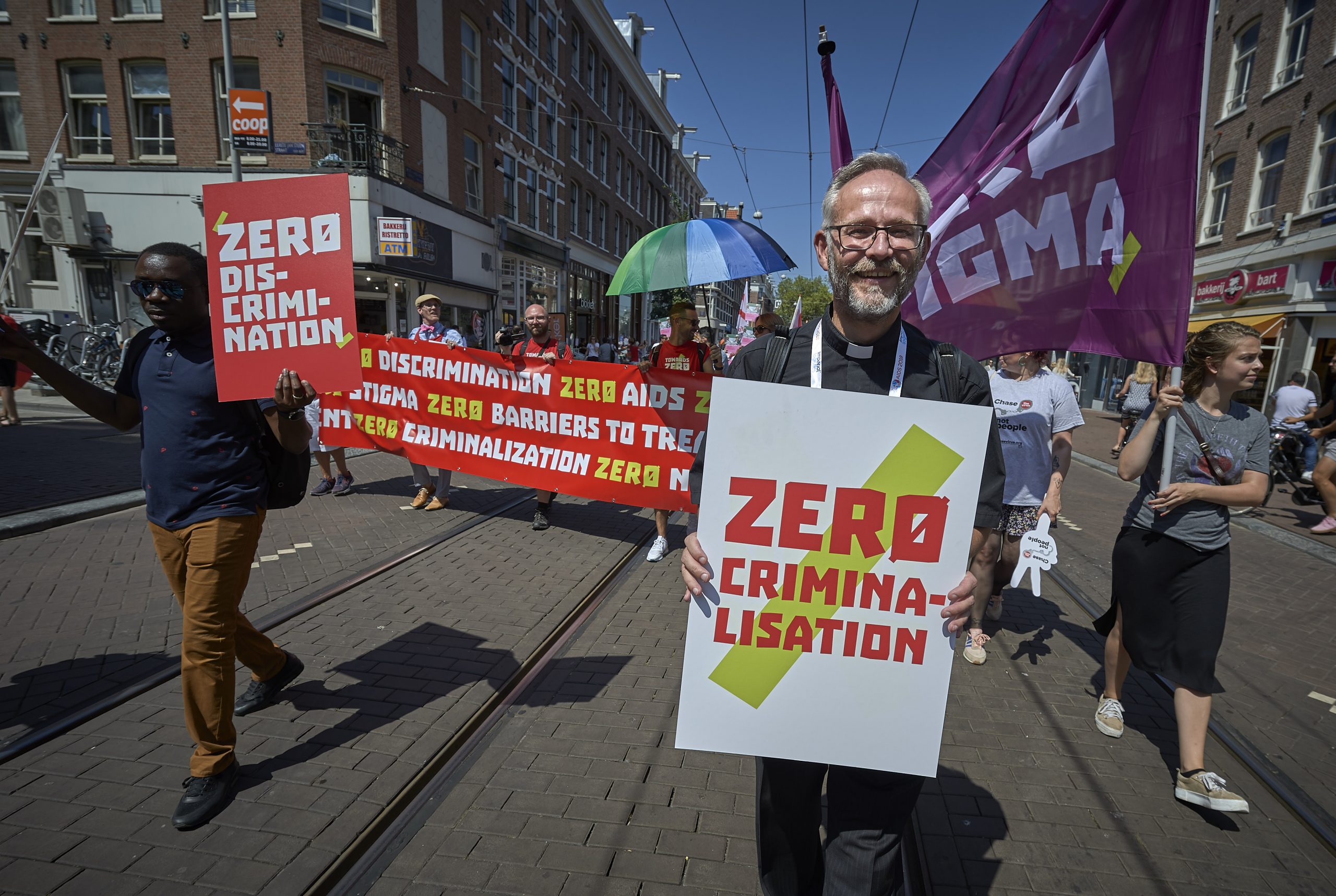 JP in a clerical collar marching with a Zero Criminalisation placard