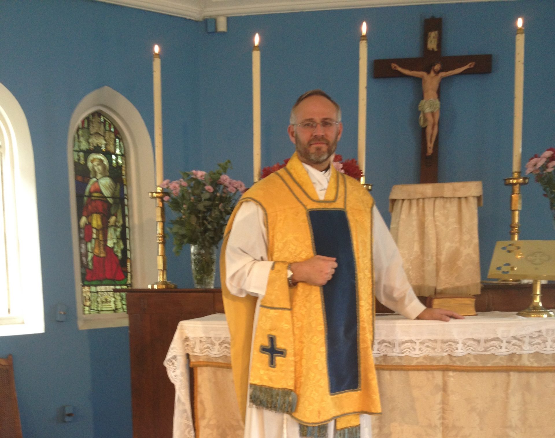 JP in a gold chasuble at the altar of a small chapel with blue walls