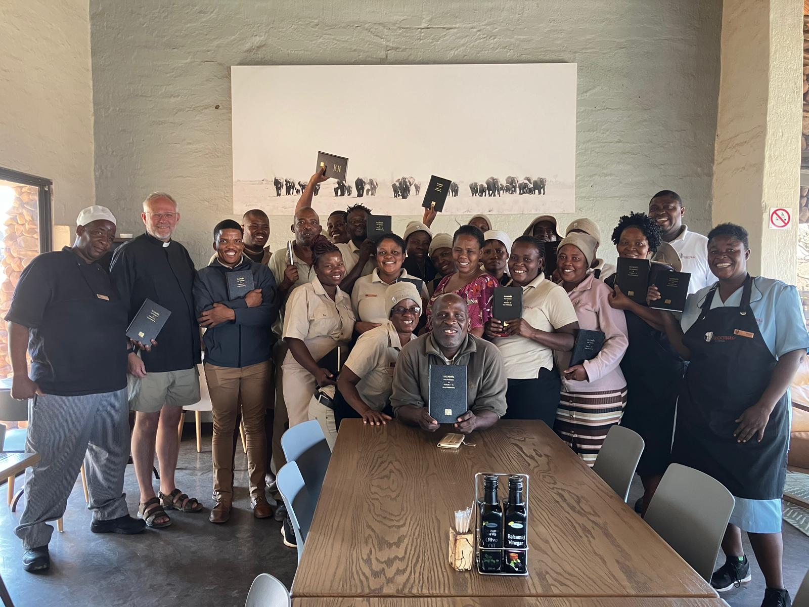 A group gathered in a hall, several holding up Bibles